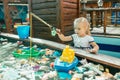 Little blonde adorable girl playing in park chasing toy fish. Summer outdor activities conÃÂept